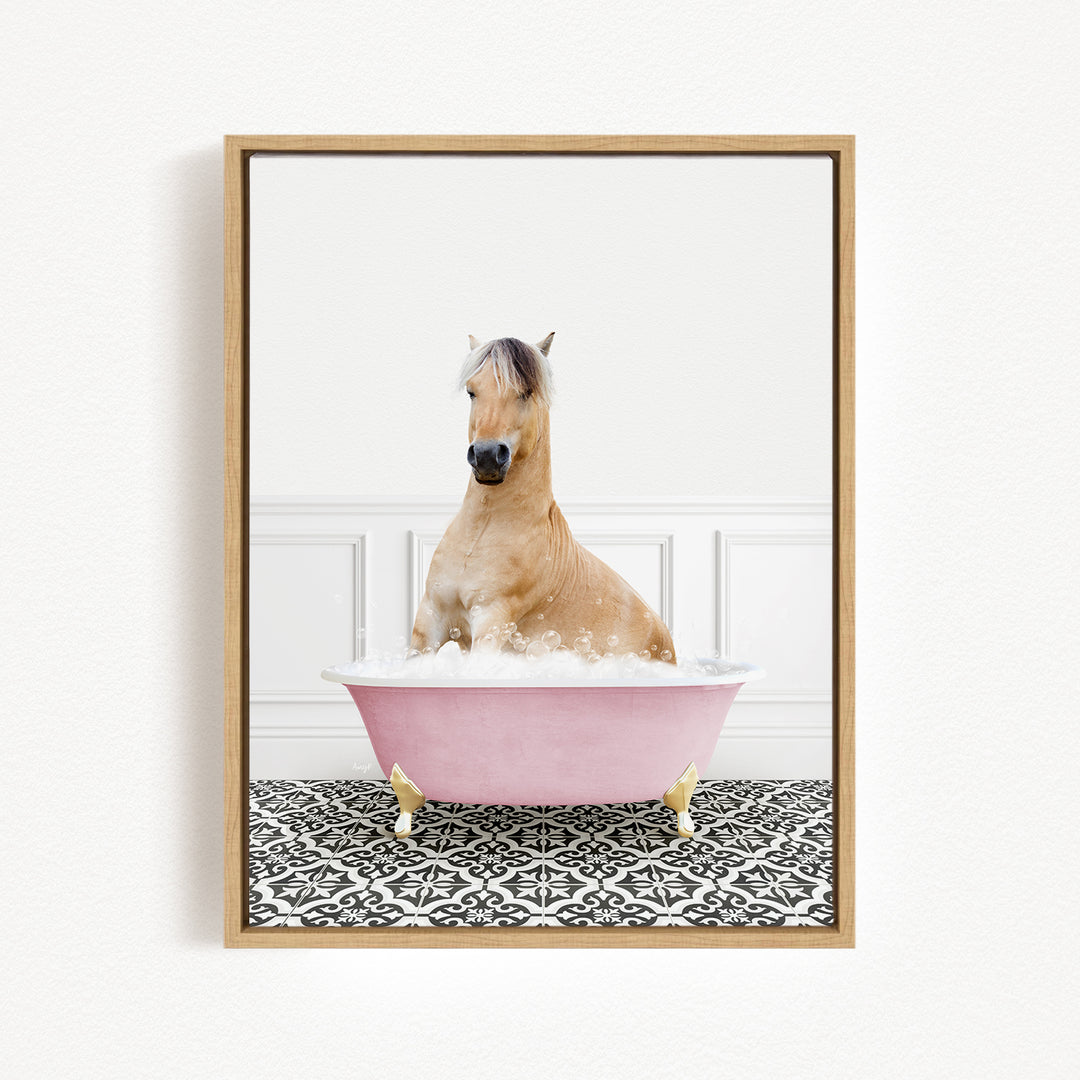 A light brown horse is sitting in a pink bathtub filled with bubbles, surrounded by a black and white patterned floor.