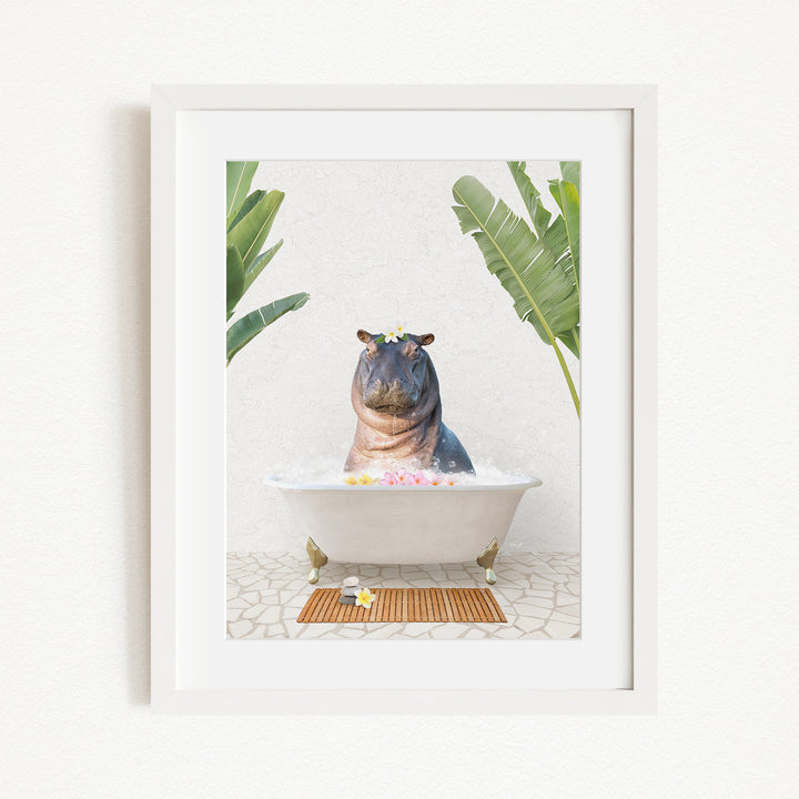 A framed image depicting a hippopotamus sitting in a bathtub filled with bubbles, surrounded by tropical plants.