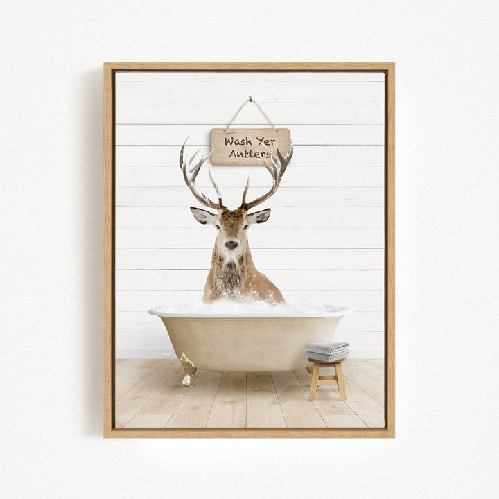 A deer with antlers is sitting in a bathtub filled with water, with a sign above it that says "Wash Your Antlers".