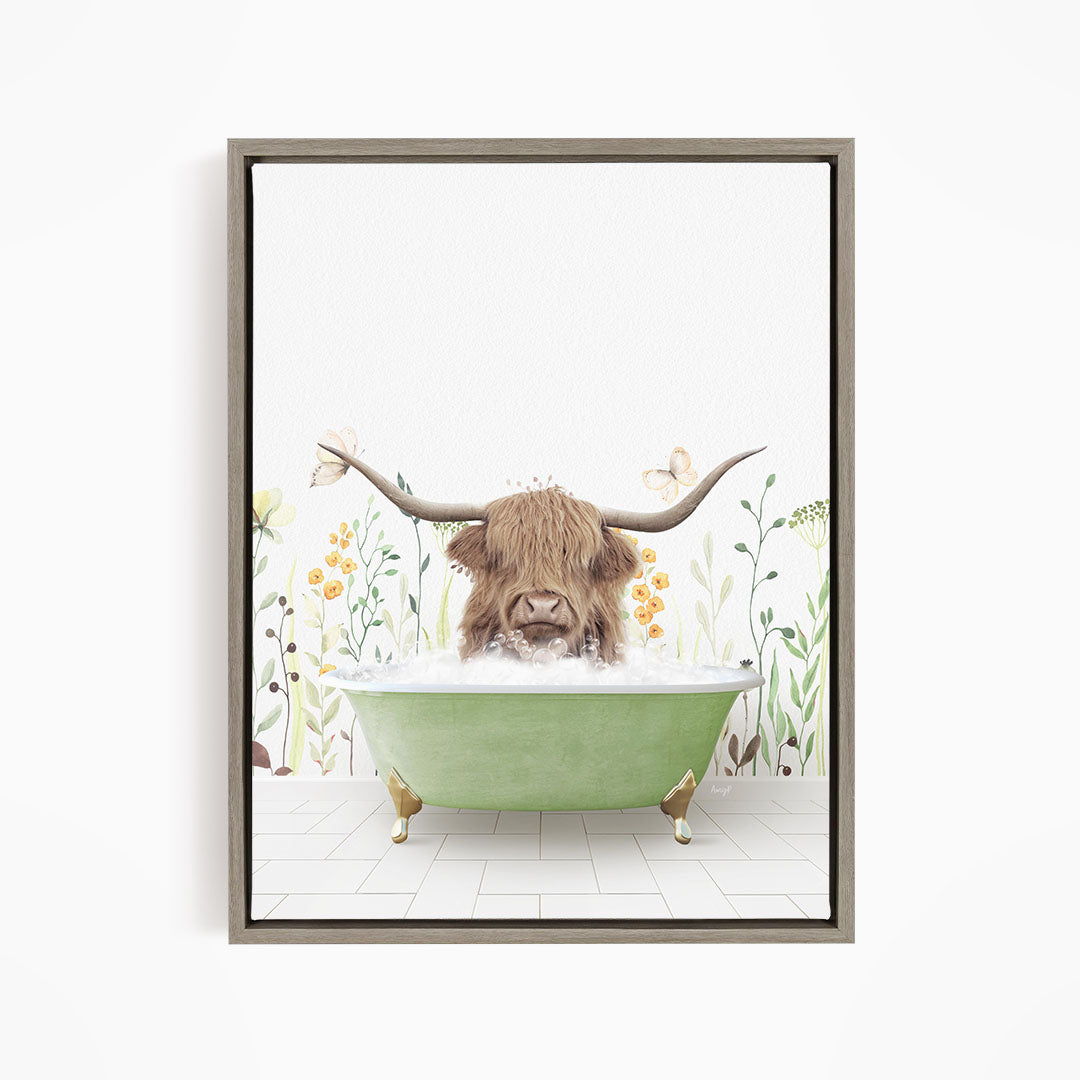 A Highland cow with large horns is sitting in a green bathtub filled with water, surrounded by flowers and plants.