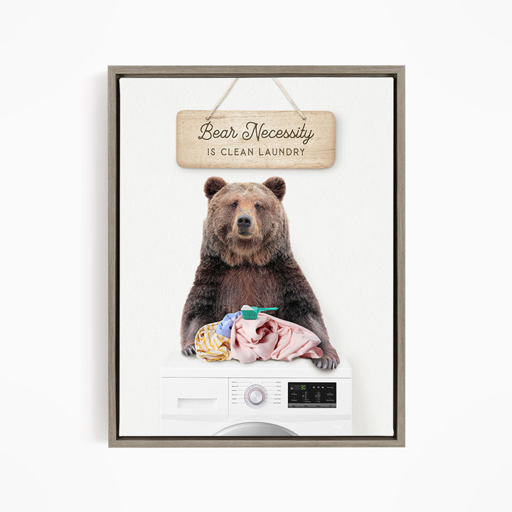 A brown bear sitting on top of a washing machine, with a sign above that says "Bear Necessity is Clean Laundry".