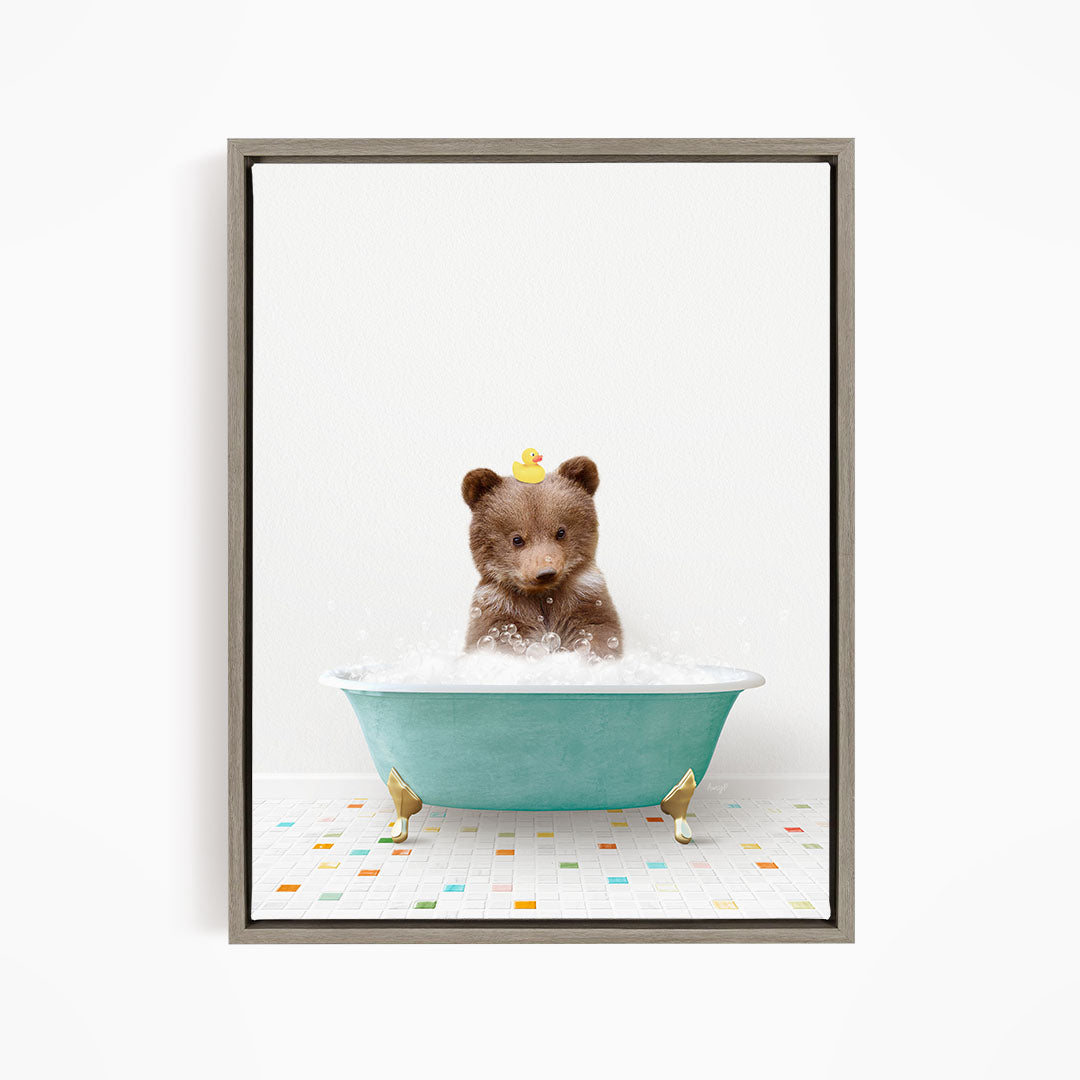 A cute brown bear sitting in a blue bathtub filled with bubbles, with a yellow rubber duck floating on its head.