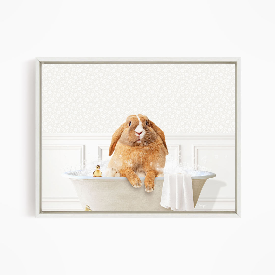 A brown rabbit sitting in a bathtub filled with water, with a towel and a small toy nearby.