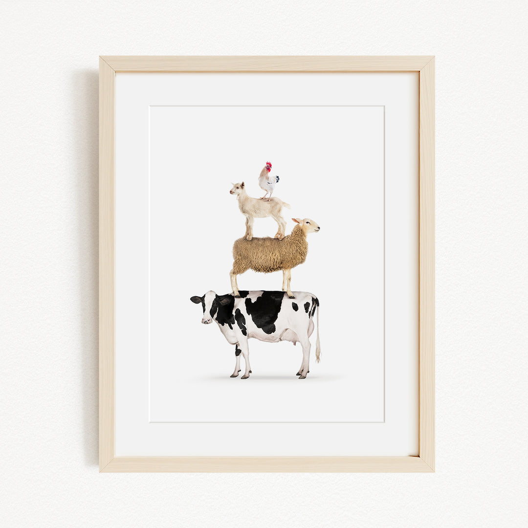 A framed image depicting a cow, sheep, and chicken stacked on top of each other.