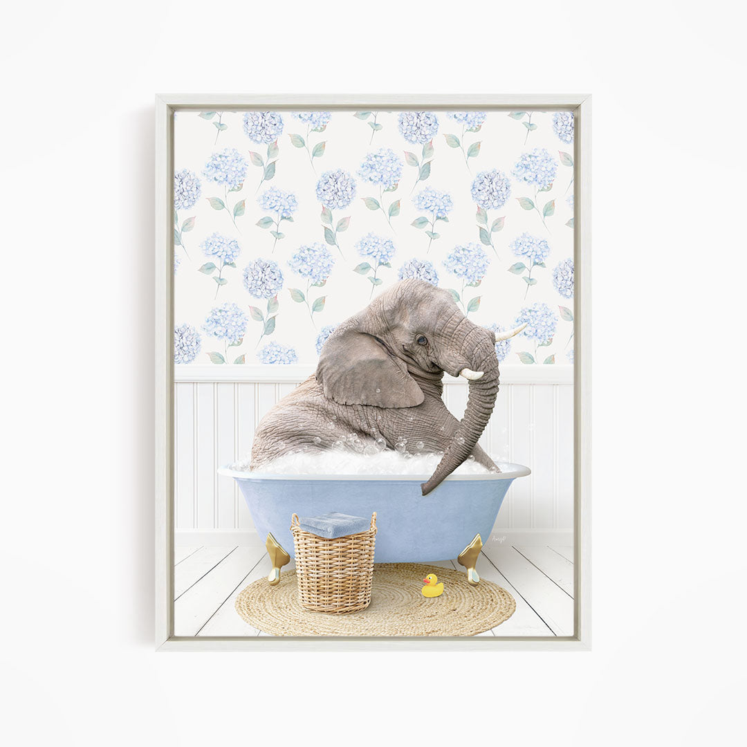A gray elephant is sitting in a blue bathtub filled with water, surrounded by a wicker basket and a yellow rubber duck.