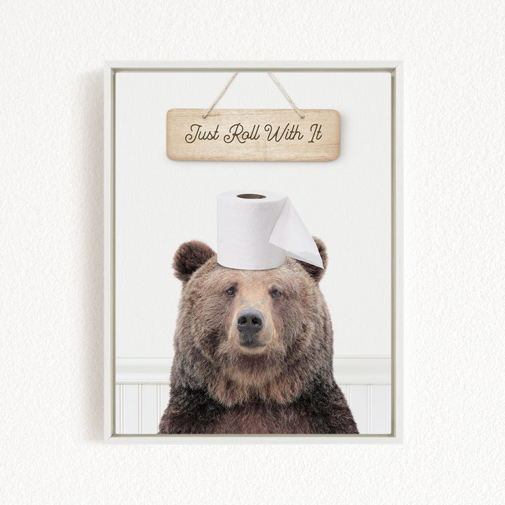 A brown bear wearing a toilet paper roll on its head, with a wooden sign above that says "Just Roll With It".