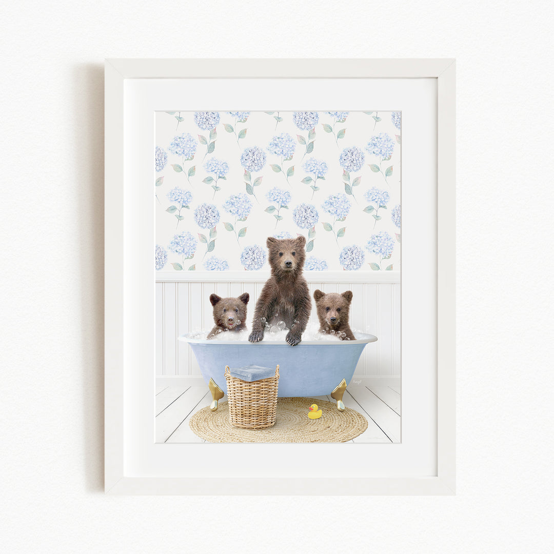 A framed image depicting three brown bears sitting in a blue bathtub, surrounded by a floral patterned wall and a yellow rubber duck.