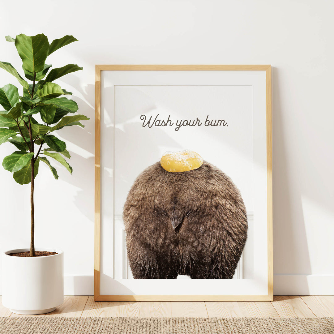 a framed poster with a picture of a bear's butt with a yellow object on it, along with the text "Wash your butt."