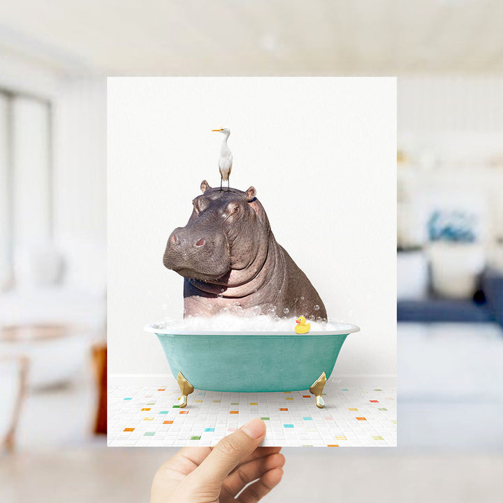 A hand holds up a collage of images depicting a hippopotamus sitting in a bathtub, with a bird perched on its head.