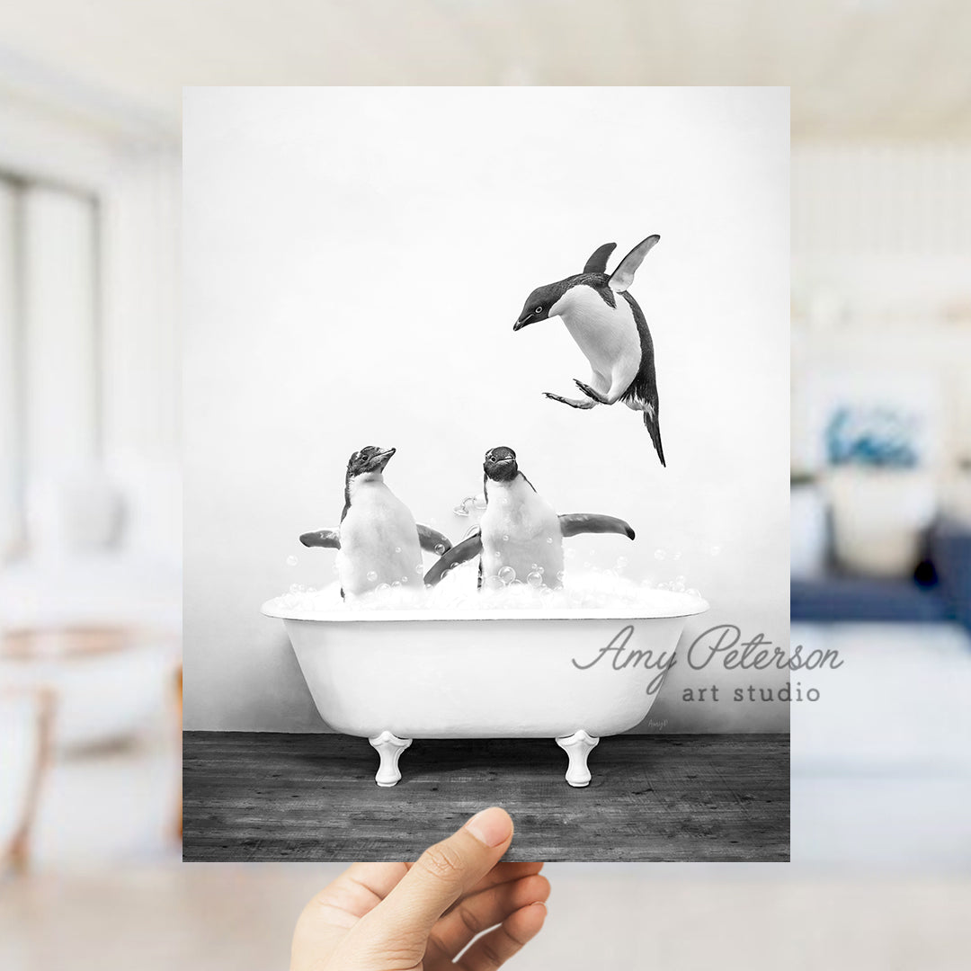 a hand holding up a card with penguins in a bathtub