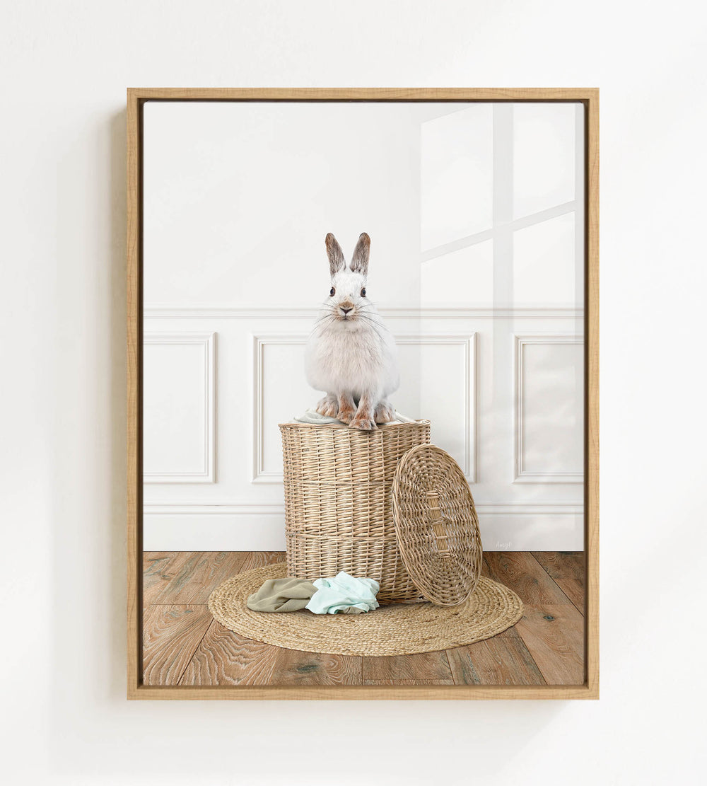 A white rabbit sits atop a woven basket on a wooden floor, with a round rug in front of it.