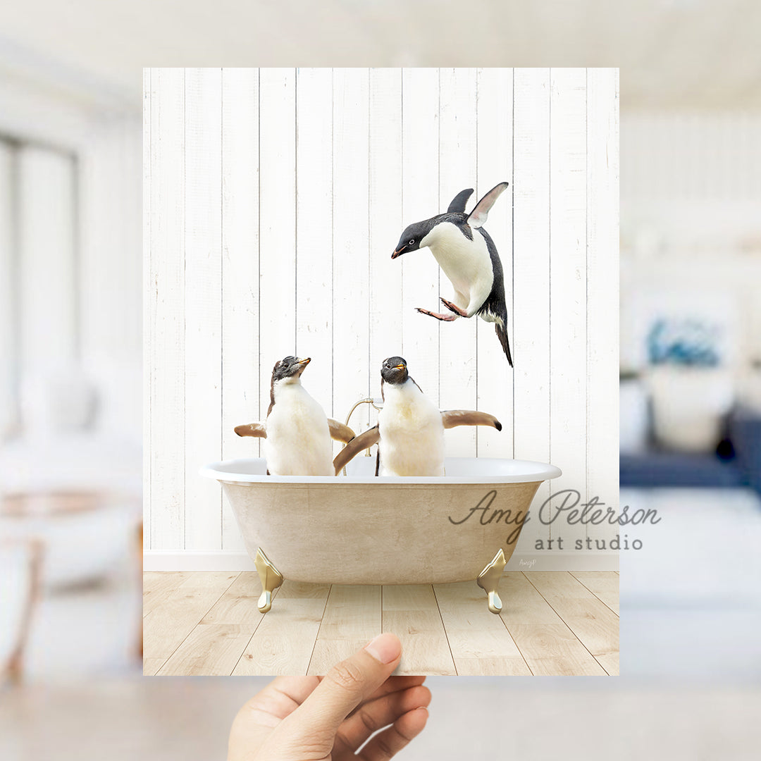 a hand holding a photo of three penguins in a bathtub