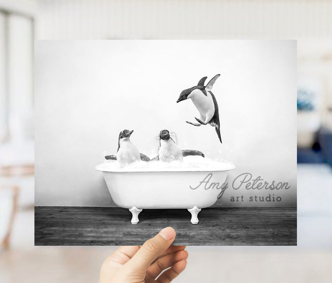 a person holding up a picture of penguins in a bathtub