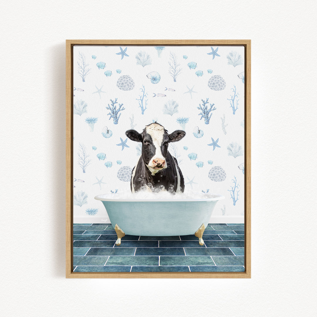 A black and white cow is sitting in a white bathtub filled with water, surrounded by a blue and white floral pattern on the wall behind it.