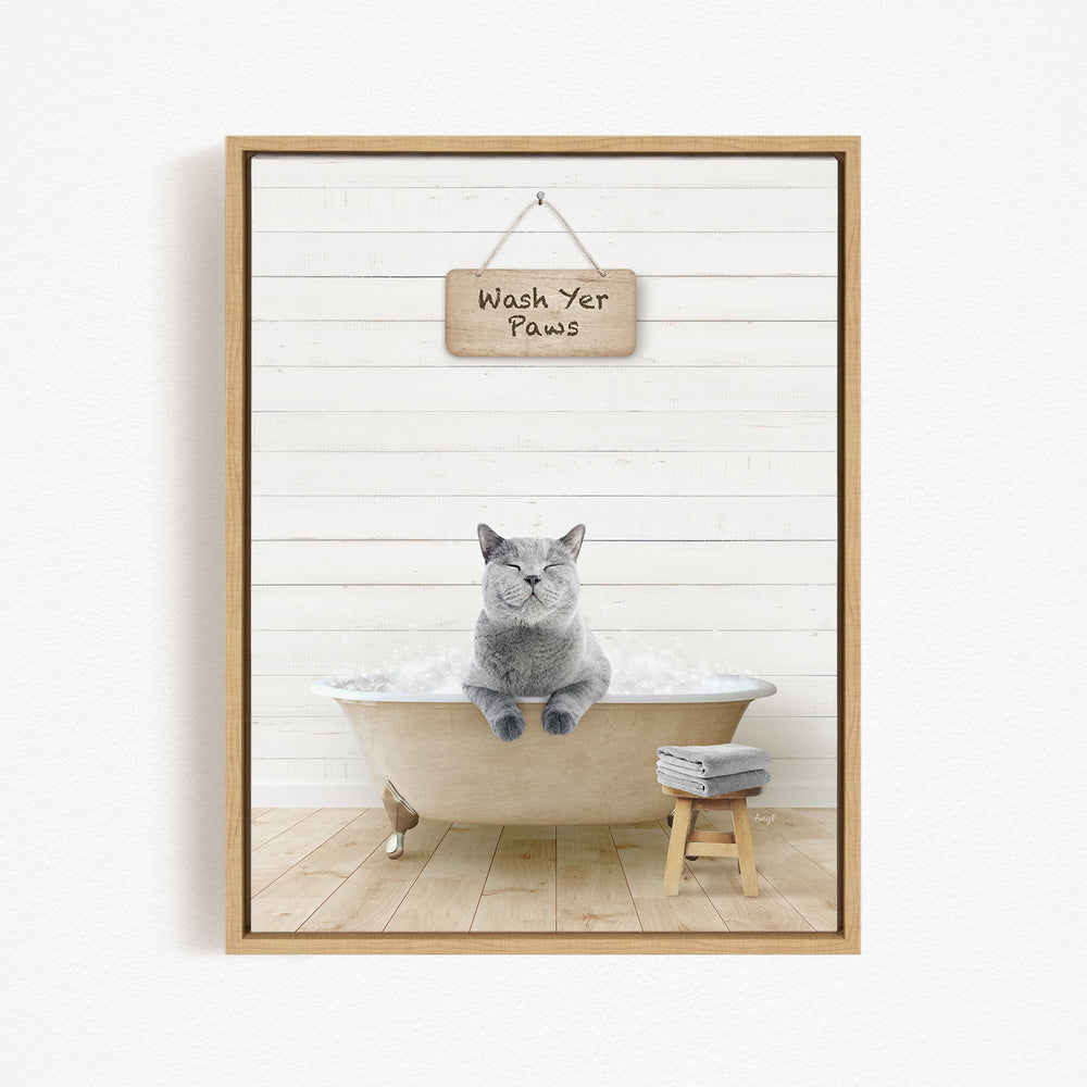 A gray cat sitting in a bathtub, with a wooden sign above that says "Wash Your Paws".