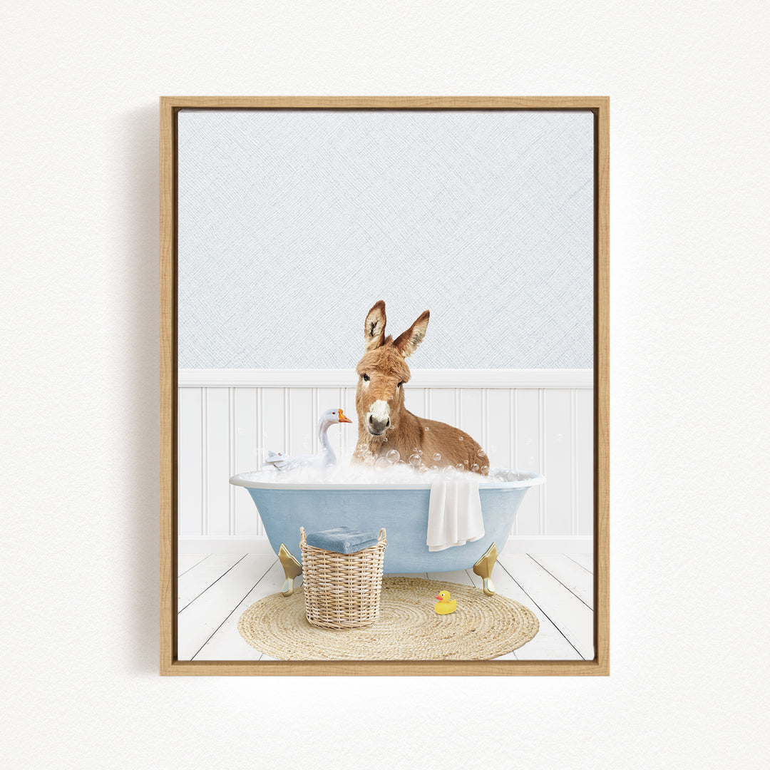 A donkey is sitting in a blue bathtub filled with bubbles, surrounded by a basket, a rubber duck, and a towel.