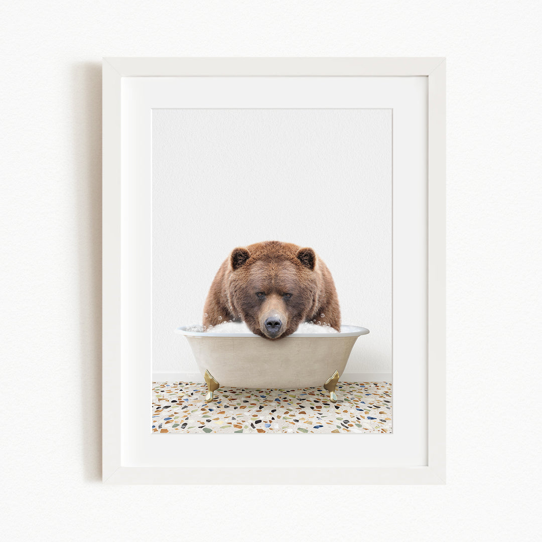 A brown bear is sitting in a white bathtub filled with water, appearing to be enjoying a relaxing bath.