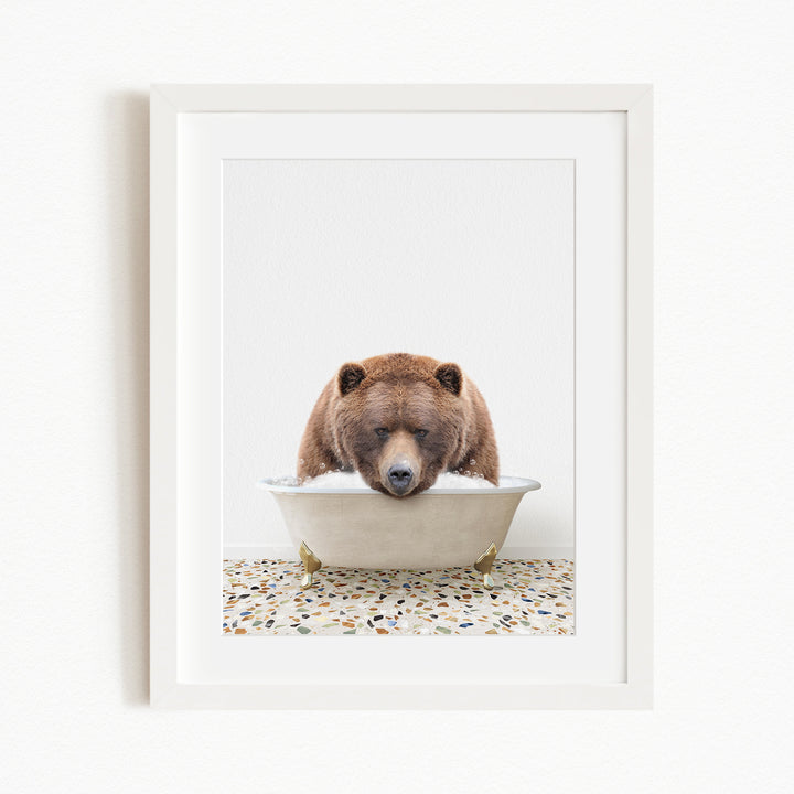A brown bear is sitting in a white bathtub filled with water, appearing to be enjoying a relaxing bath.