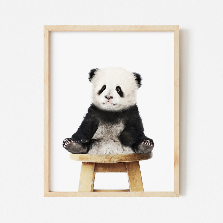 a panda bear sitting on top of a wooden stool