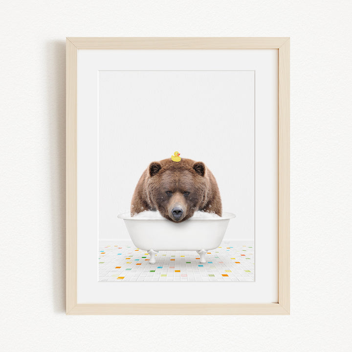 A brown bear is sitting in a white bathtub, with a yellow rubber duck perched on its head.