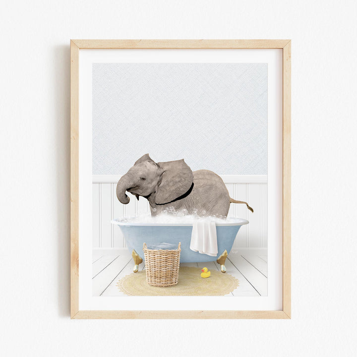 A gray elephant is sitting in a blue bathtub filled with water, surrounded by a yellow rubber duck and a wicker basket.