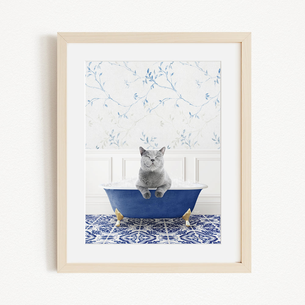 A gray cat sitting in a blue bathtub, with a patterned tile floor and a floral wallpaper in the background.