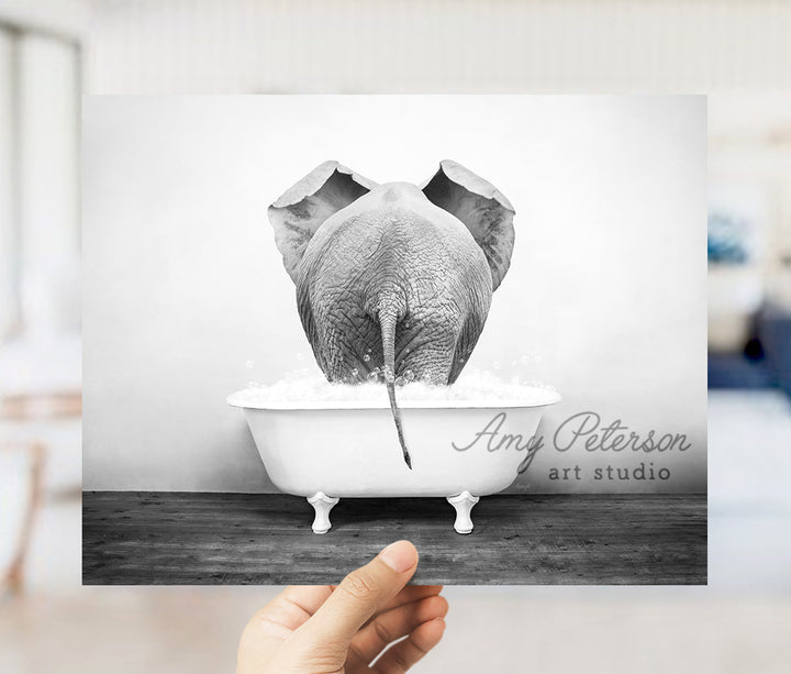 a person holding up a picture of an elephant in a bathtub