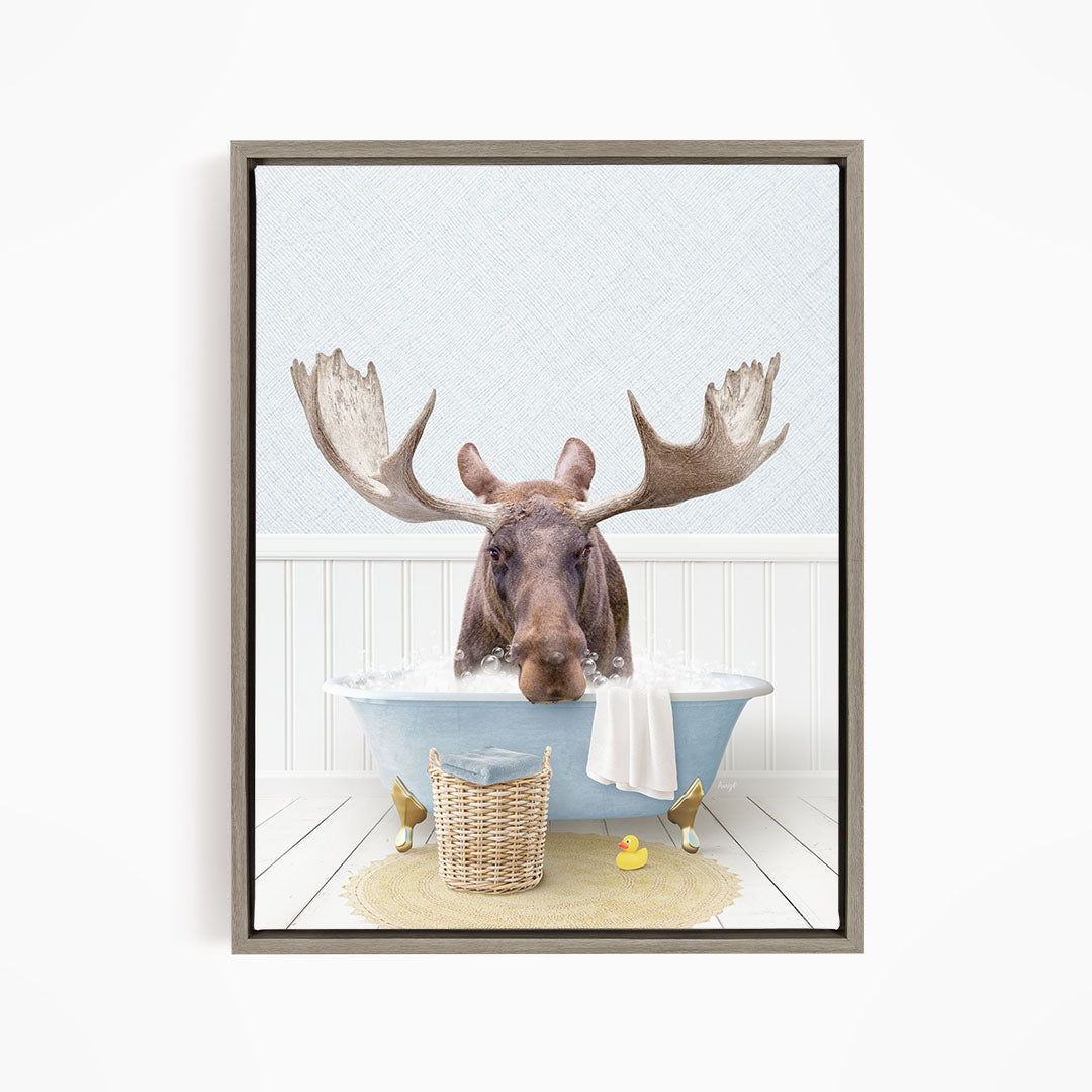 A moose with large antlers is sitting in a bathtub filled with water, surrounded by rubber ducks.