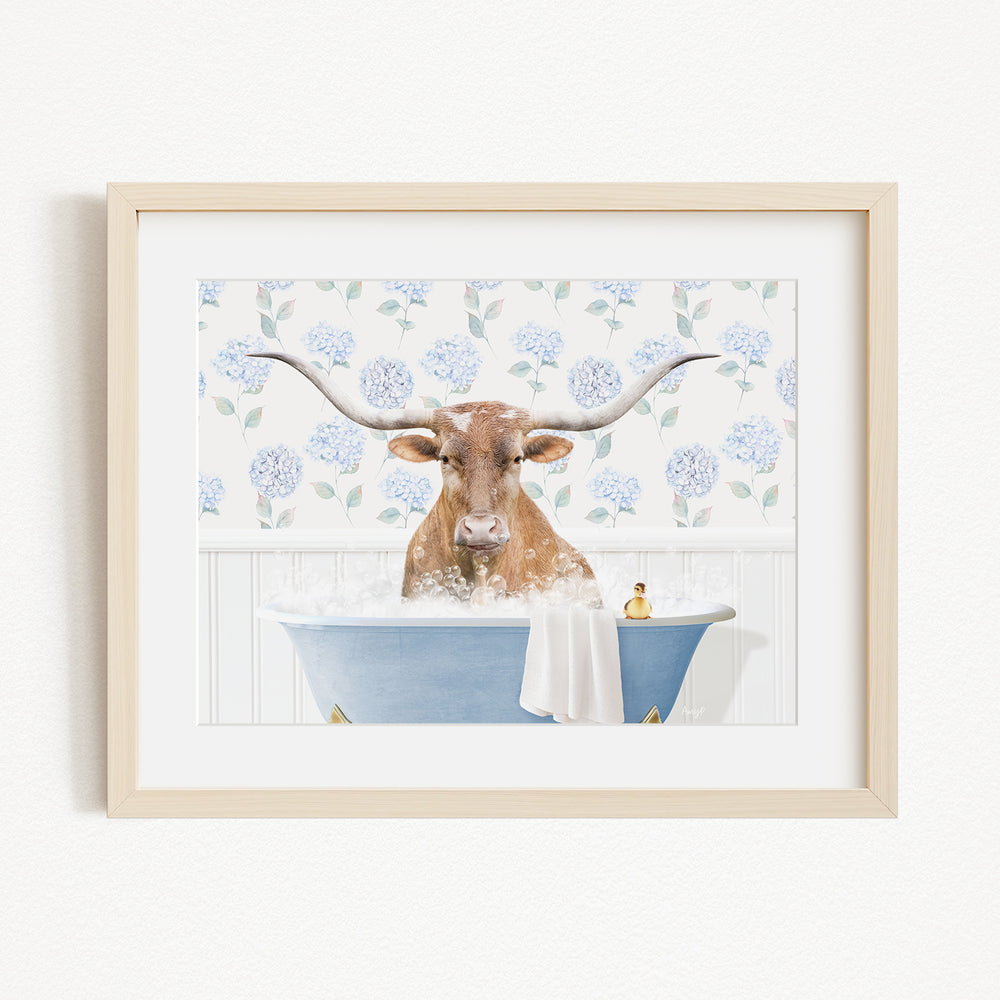 A brown cow with large horns is sitting in a blue bathtub filled with bubbles, surrounded by a floral patterned wall.