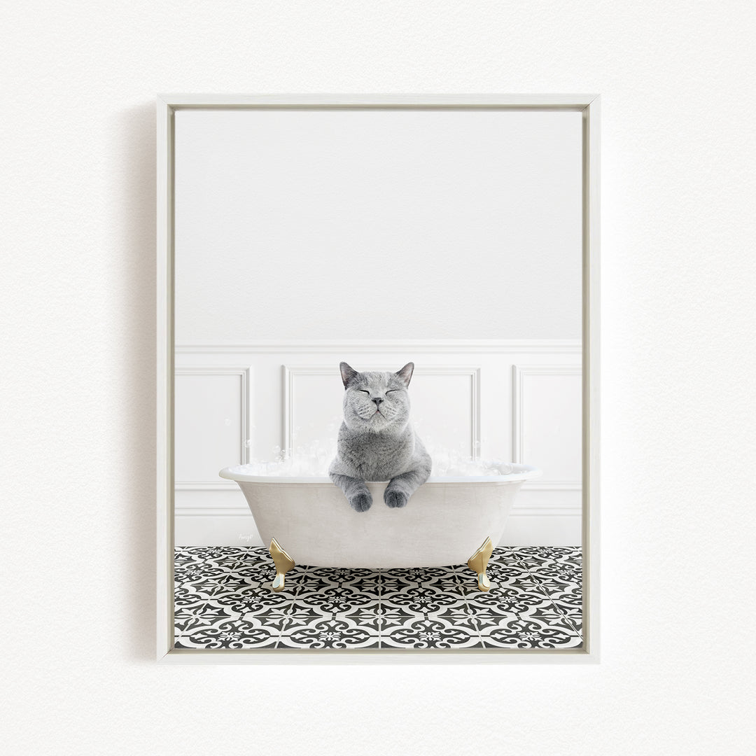 A gray cat sitting in a white bathtub filled with bubbles, surrounded by a black and white patterned floor.