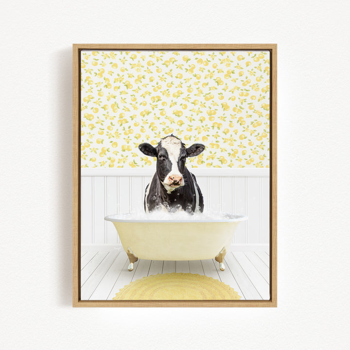 A black and white cow is sitting in a white bathtub filled with bubbles, surrounded by a yellow floral wallpaper.