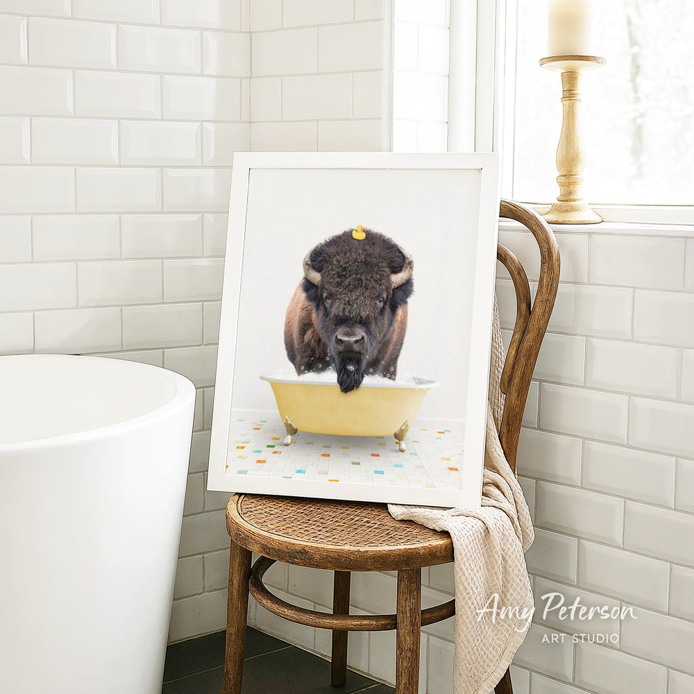 A framed image of a bison sitting in a bathtub, with a rubber duck floating on the water.