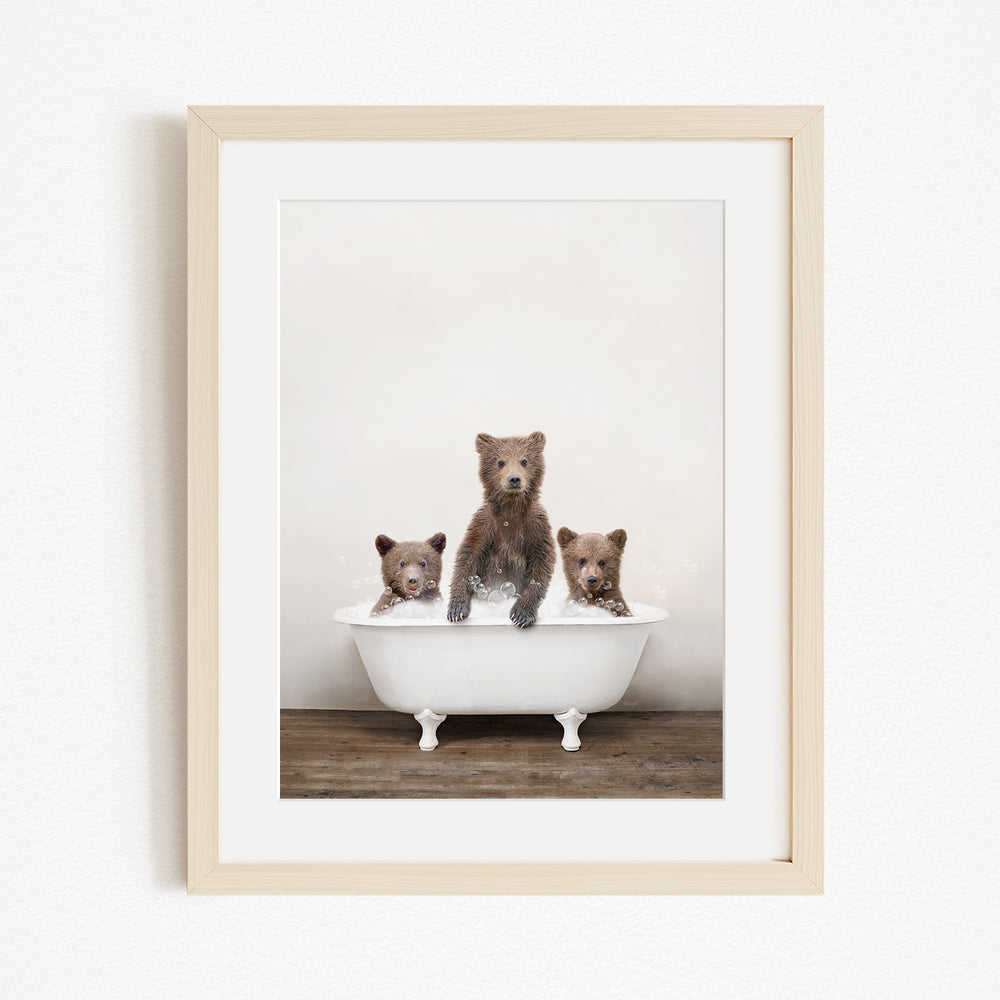 A framed image depicting three brown bears sitting in a white bathtub, with one bear sitting in the center and the other two bears sitting on either side.
