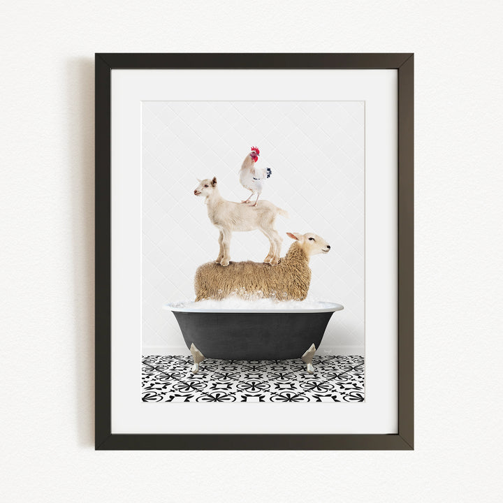A framed image depicting a white goat standing on top of a sheep in a bathtub, with a rooster perched on the sheep's back.