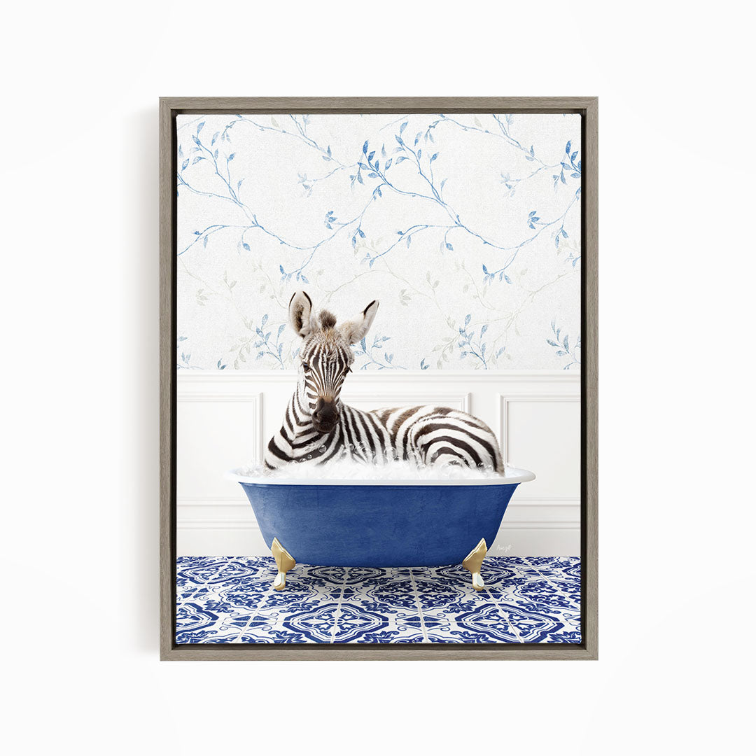 A zebra is sitting in a blue bathtub, surrounded by a patterned tile floor and a floral wallpaper background.