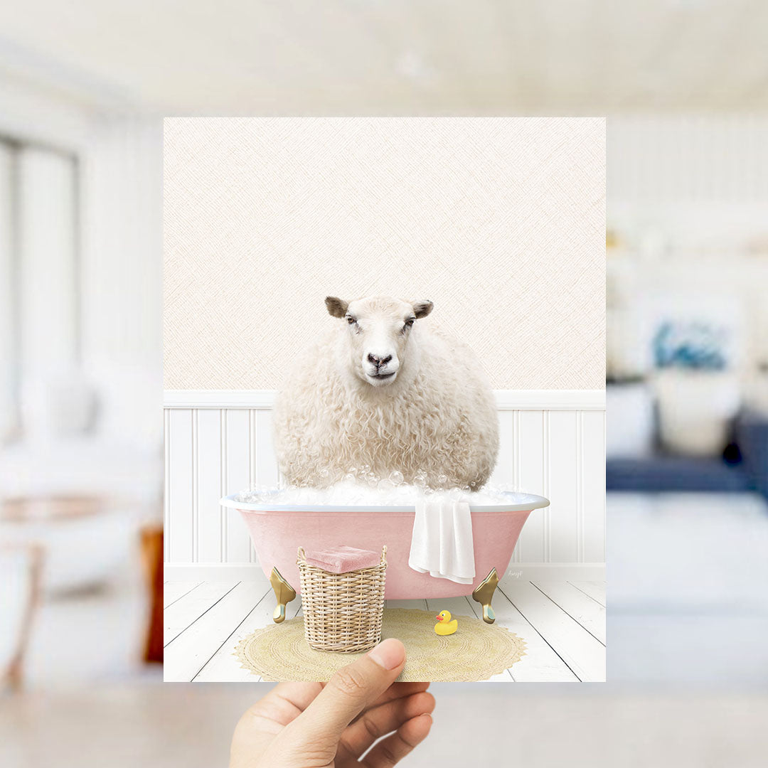 A fluffy white sheep sits in a pink bathtub filled with bubbles, surrounded by a yellow rubber duck and a white towel.