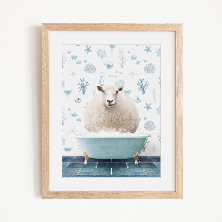 A framed image depicting a fluffy white sheep sitting in a blue bathtub filled with bubbles, surrounded by a pattern of blue and white seashells and starfish.