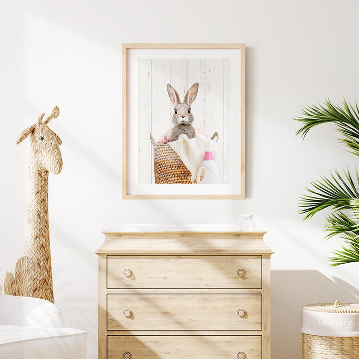 a wooden dresser with a framed picture of a rabbit and a giraffe on it, along with a small stuffed animal. The dresser is situated in a room with a white wall and a potted plant nearby.