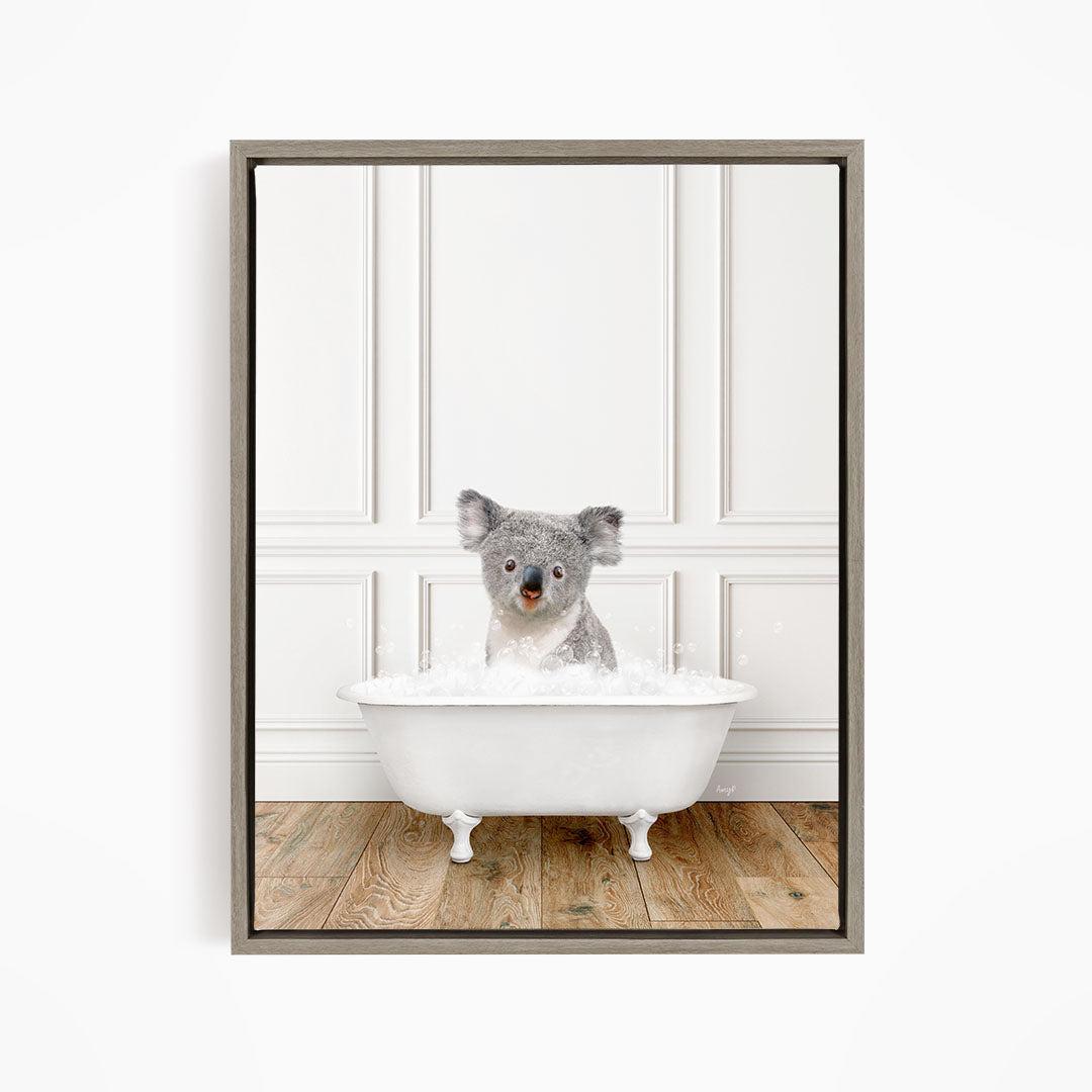 A koala bear sitting in a white bathtub filled with bubbles, looking directly at the camera.