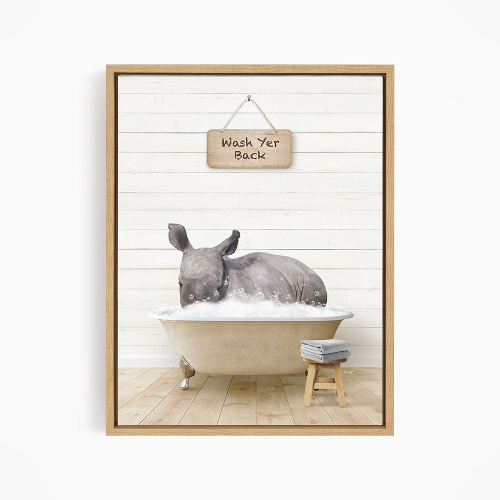 A rhinoceros is sitting in a bathtub filled with water, with a wooden sign above it that says "Wash Yer Back".