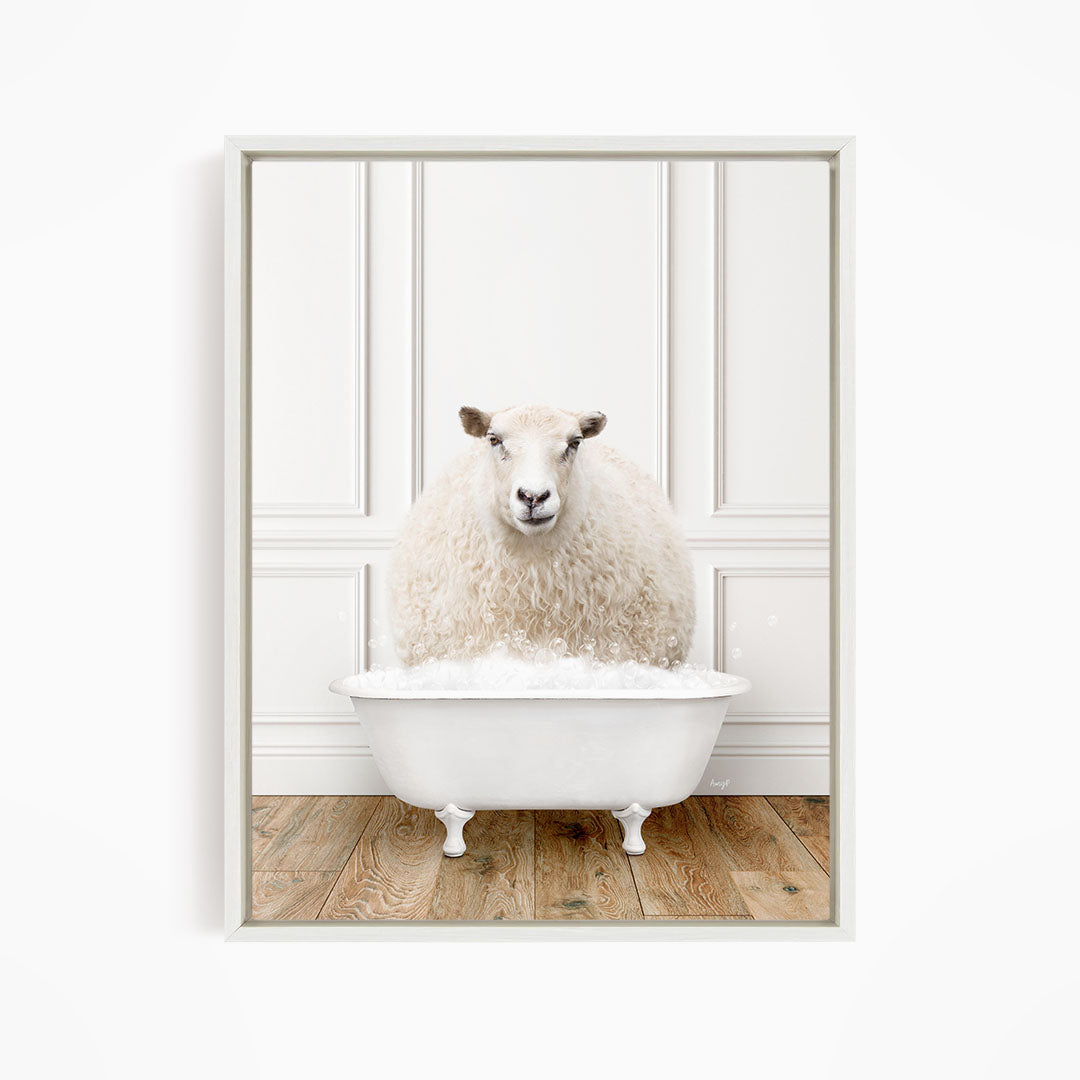 A fluffy white sheep sits in a white bathtub filled with bubbles, looking directly at the camera.