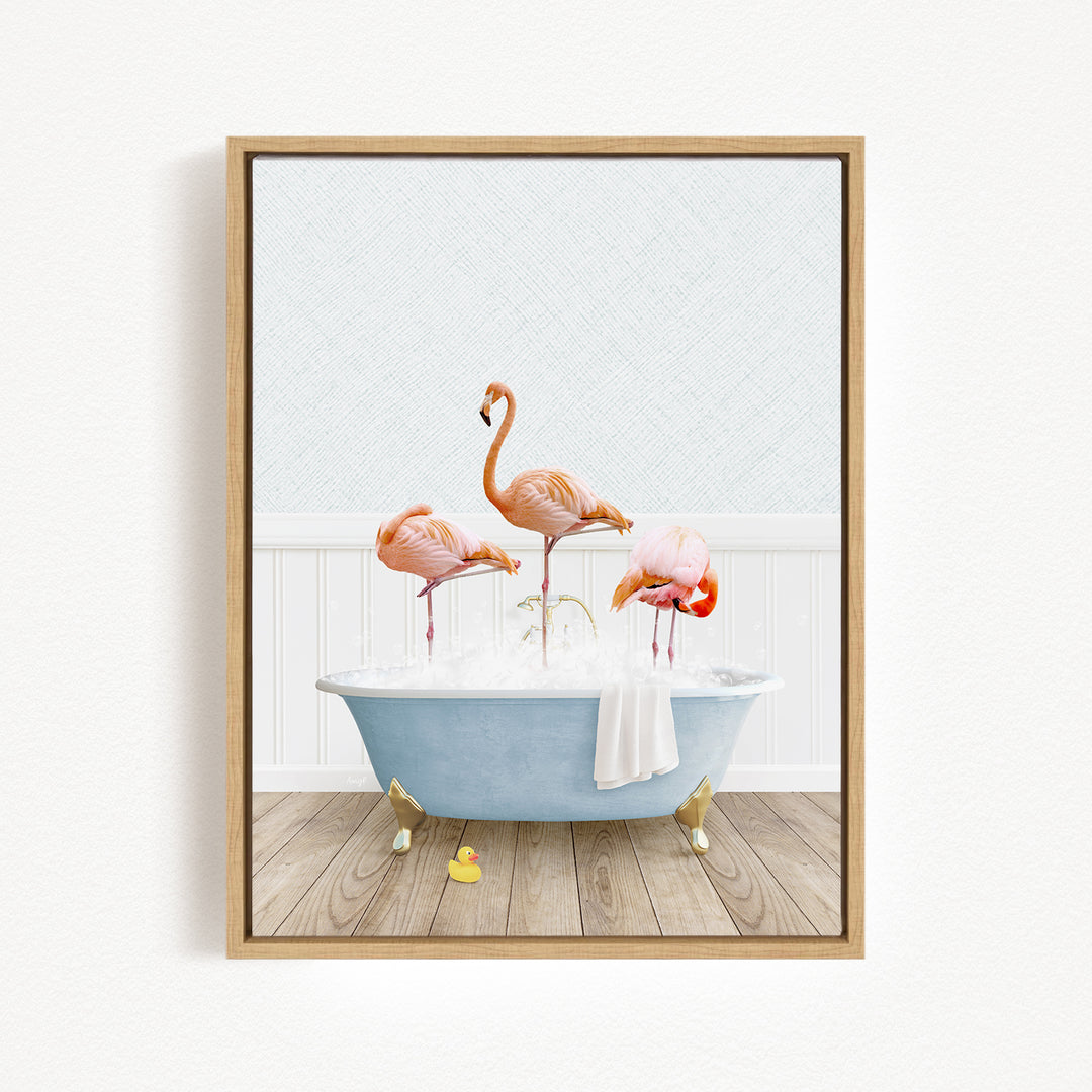A framed image depicting three flamingos standing in a blue bathtub filled with water, with a white towel hanging on the side.