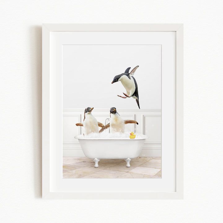 A framed image depicting three penguins enjoying a bath in a white bathtub, with one penguin flying towards the tub.