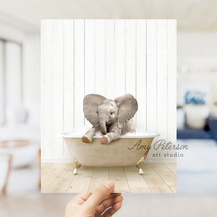 a hand holding up a picture of an elephant in a bathtub