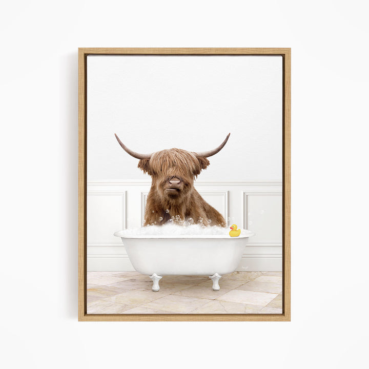 A brown cow with long horns is sitting in a white bathtub filled with water, with a yellow rubber duck floating in the tub.