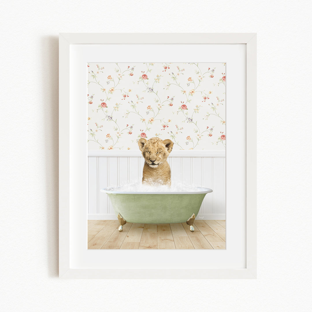 A young lion cub sitting in a green bathtub filled with water, with a floral wallpaper in the background.