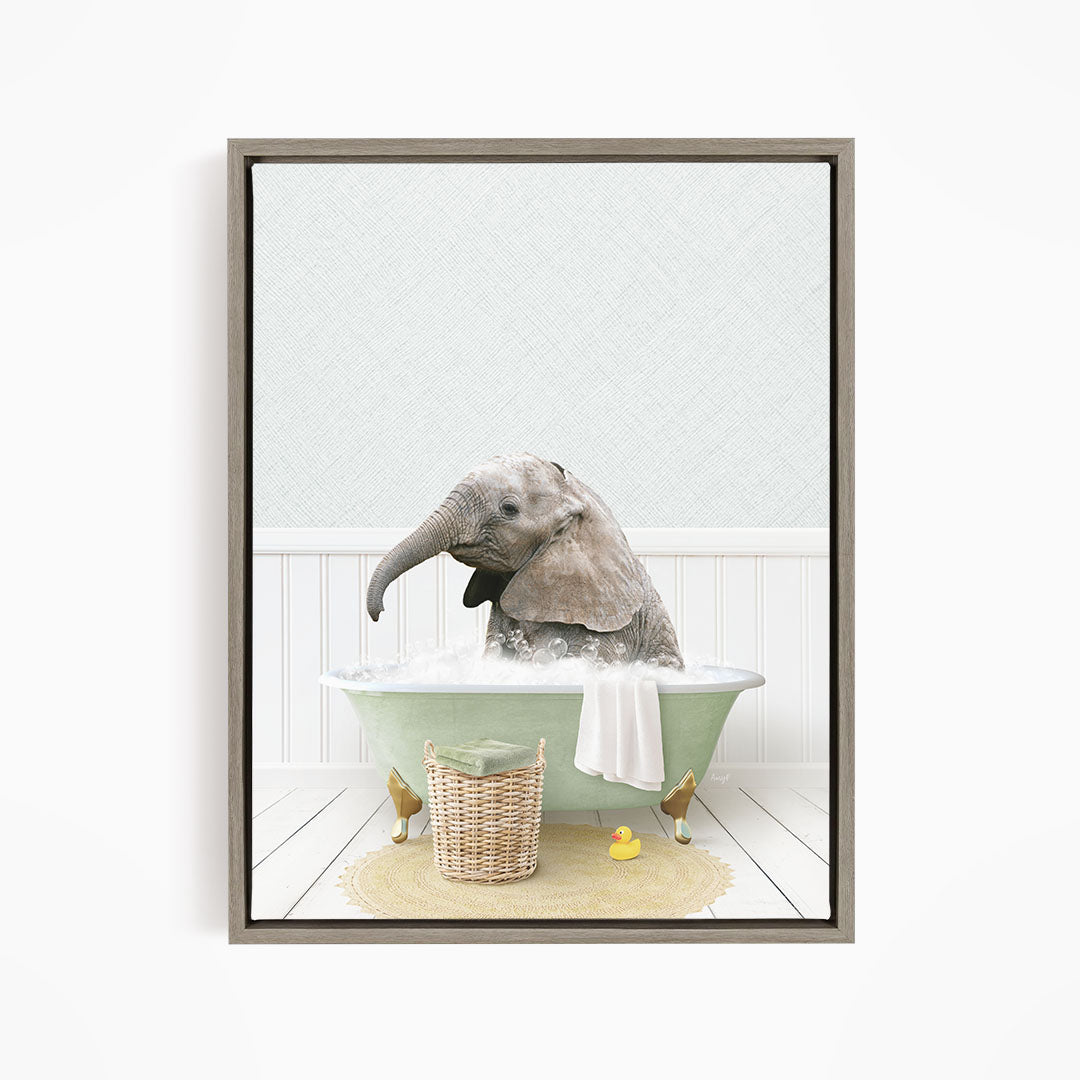 A gray elephant is sitting in a green bathtub filled with water, surrounded by a basket of toys and a yellow rubber duck.