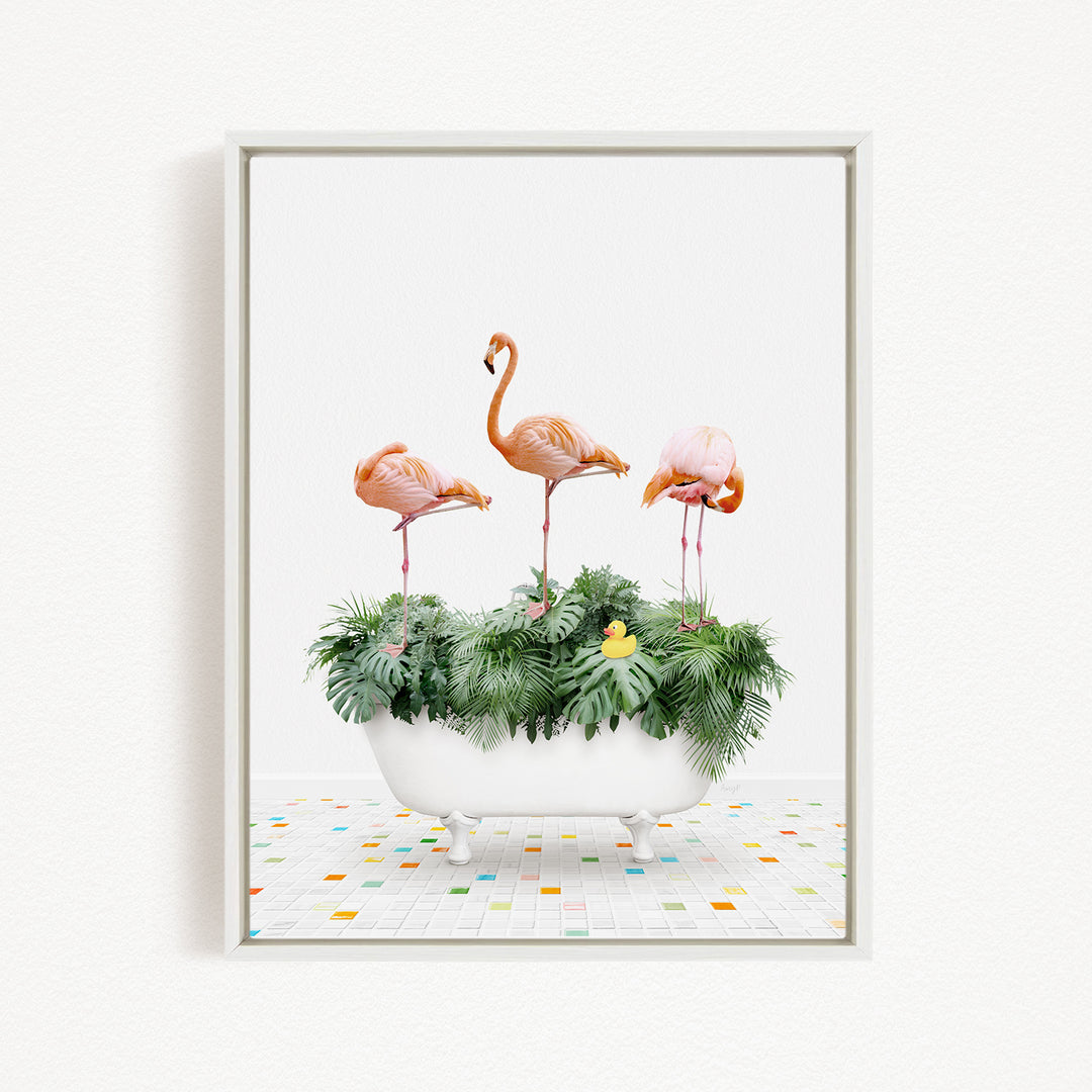 A framed image depicting three flamingos standing in a white bathtub filled with green plants and a yellow rubber duck.