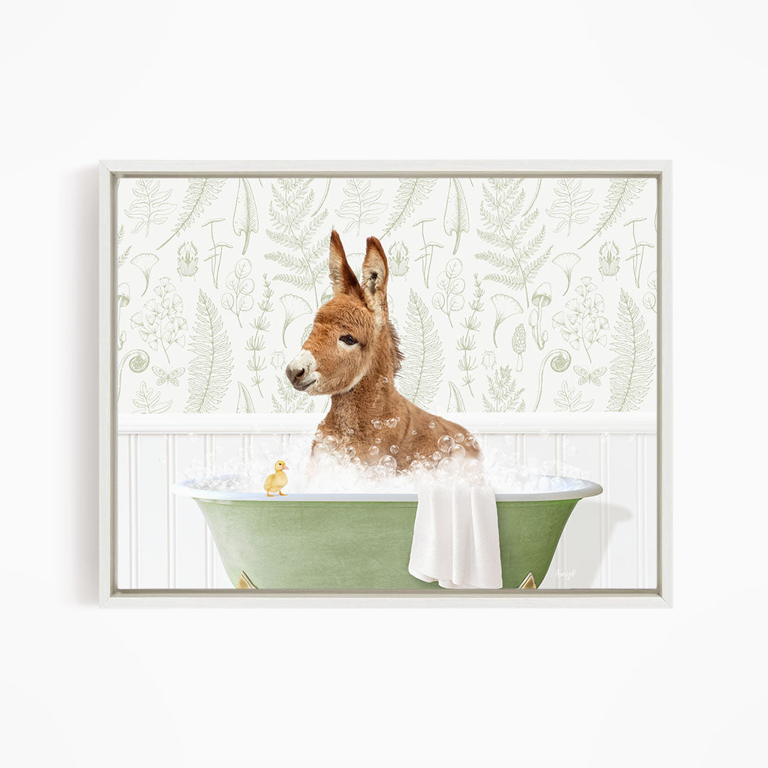 A brown kangaroo is sitting in a green bathtub filled with water, surrounded by a white towel and a small yellow duck.
