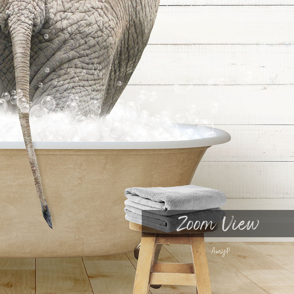 A large elephant is standing in a bathtub filled with bubbles, with a towel and stool visible in the foreground.